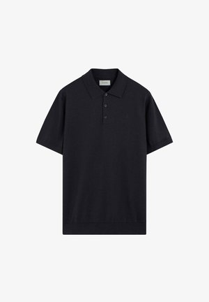 Camiseta polo negra de manga corta con cuello y tres botones, mostrada extendida sobre un fondo blanco.