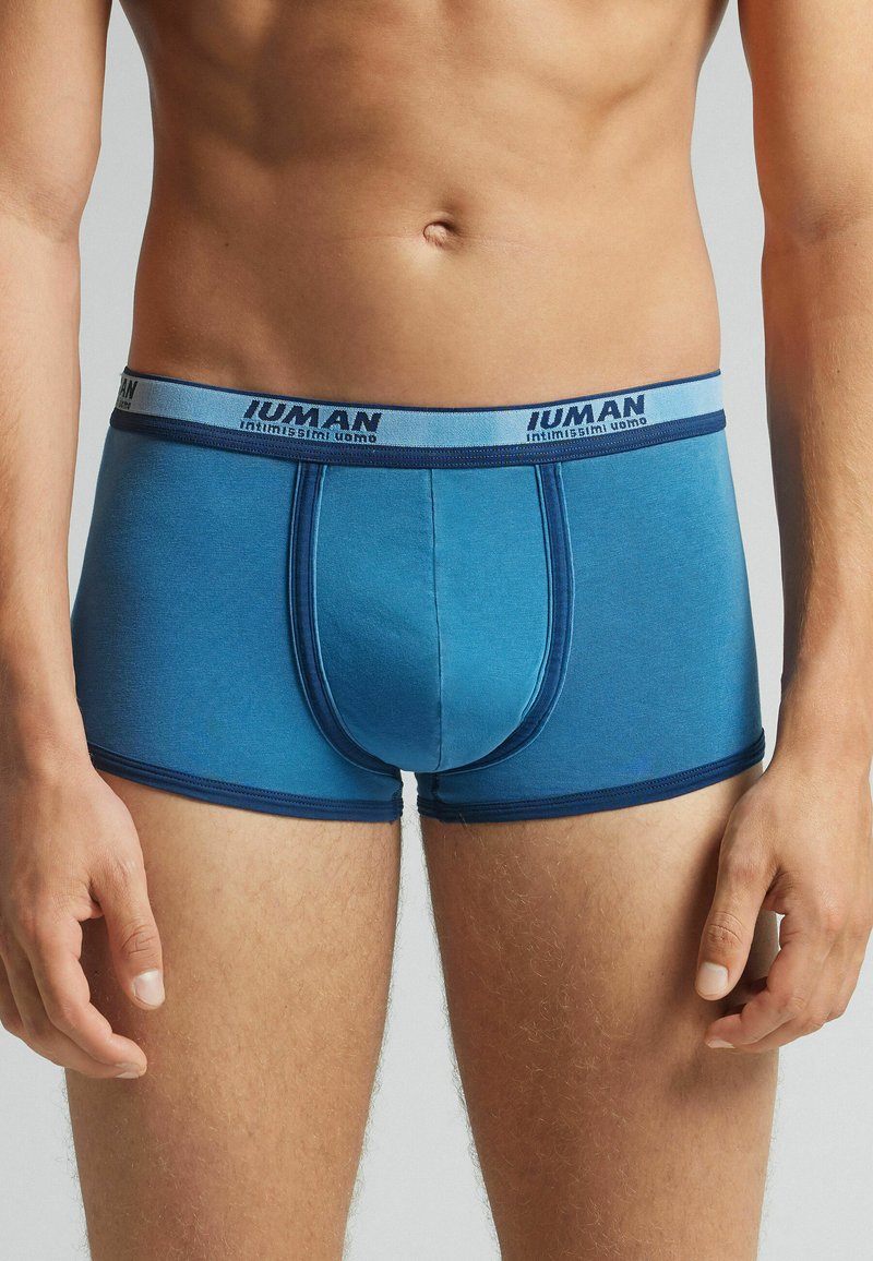 Blaue Boxershorts aus weichem Stoff, mit einem kontrastierenden dunkelblauen Bund mit Logo der Marke und einem eng anliegenden, figurbetonten Design.