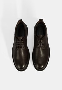 Bruine leren schoenen met een gestructureerde afwerking, ronde neuzen en standaard vetersluiting. Zachte voering en duurzame rubberen zolen.