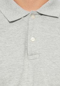Polo gris avec un motif en tricot texturé, doté d'un col classique et de trois boutons au plastron. Tissu doux.
