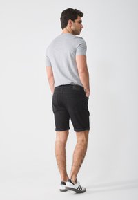 Gray short-sleeve t-shirt, black rolled-up shorts, and white sneakers with black accents. Smooth fabric and classic fit. Minimalist design.