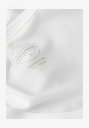 Hvidt stof, der viser et plejelabel med teksten "Intimissimi S Designet i Italien Fremstillet i Serbien" i lys gråtryk. Glat tekstur.