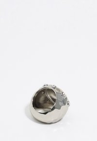 Anillo de plata metálica con una forma orgánica y texturizada, que presenta pequeñas piedras preciosas transparentes incrustadas en su superficie. Forro interior suave.