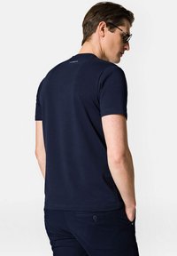 Granatowa koszulka z krótkim rękawem, wykonana z gładkiego materiału bawełnianego, z okrągłym dekoltem i prostym wzorem z tyłu z detalem logo.