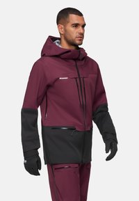 Bordeaux- und schwarze wasserdichte Jacke mit Kapuze, mehreren mit Reißverschluss versehenen Taschen und elastischen Bündchen. Der Stoff hat eine glatte, matte Oberfläche.