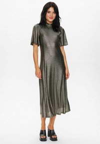 Metallic green midi dress with short, flutter sleeves and a high neckline. Shiny, textured fabric with a straight fit, paired with black platform heels.