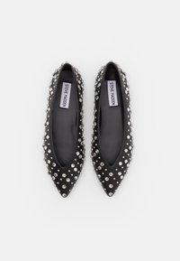 Ballerines noires à bout pointu ornées de clous argentés couvrant uniformément la surface, avec l'étiquette Steve Madden à l'intérieur de chaque chaussure.