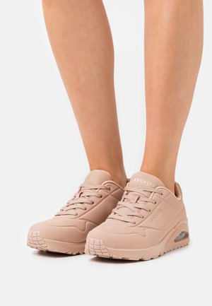 Sneaker Skechers in rosa chiaro, realizzati in materiale sintetico, con dettagli perforati, lacci piatti e un cuscinetto d'aria visibile nella suola.