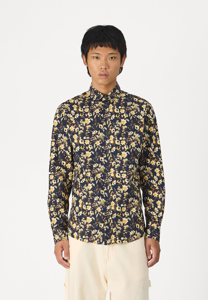 Chemise à manches longues à boutons en bleu marine avec un motif floral comportant des fleurs jaunes. Fabriquée en tissu léger, elle possède un col classique et une coupe régulière.