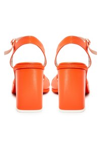 Paire de sandales à talons hauts orange vif avec sangles à la cheville et talons blocs vues de dos sur fond blanc.