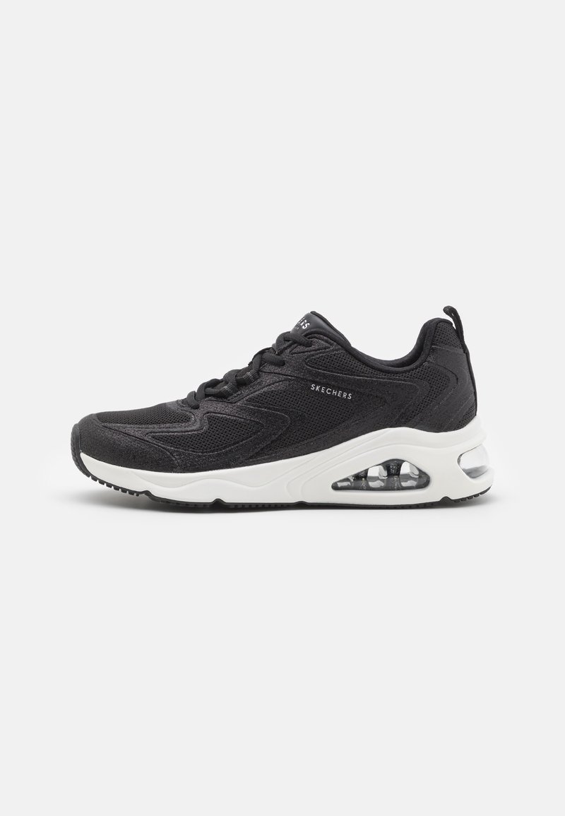 Black athletic shoes with mesh upper, white sole, and visible air cushioning. Features textured sides and contrasting rubber outsole.