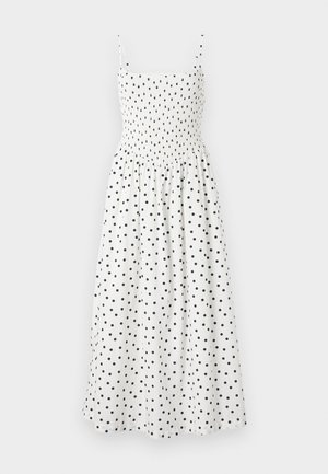 White midi dress with black polka dots, featuring a smocked bodice, thin shoulder straps, and a flowy skirt. Soft fabric with a light texture.