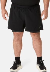 Zwarte sportshorts met een elastische tailleband, voorzien van zijzakken en een lichtgewicht stof. Draag met zwarte sneakers en sokken.