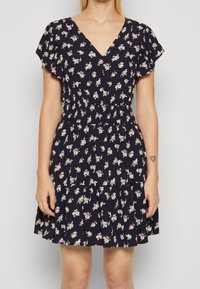 Marineblaues Kleid mit kurzen, flatternden Ärmeln und einem V-Ausschnitt. Verfügt über eine taillierte Passform mit einem elastischen Bund und floralen Mustern über das gesamte Kleid.