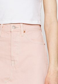 Gonna di jeans rosa con vita alta, dotata di cinque tasche, cuciture a contrasto e chiusura con bottone metallico sul davanti.