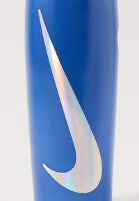 Sile sinine veepudel, mis on valmistatud siledast plastikust turgutava viimistlusega; sellel on iridescentne Nike Swoosh logo.