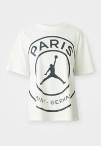 T-shirt en coton blanc avec un design graphique noir ornant le mot "PARIS" et la silhouette d'un joueur de basket. Manches courtes, coupe décontractée.