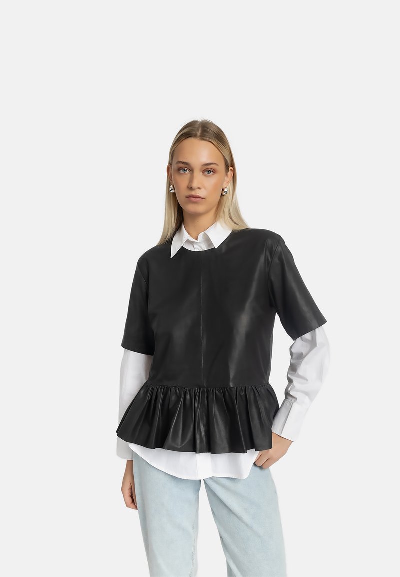 Schwarzes Leder-Peplum-Top mit kurzen Ärmeln, strukturierter Oberfläche und gerafftem Saum. Wird über einem weißen Button-up-Hemd getragen.