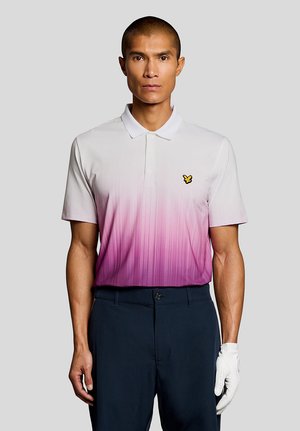Mand iført en polo med hvidt og pink gradient, marineblå bukser og en hvid golfhandske på venstre hånd, stående mod en ensfarvet baggrund.