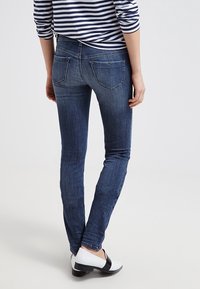 Smal jeans i blå denim med två bakfickor, en slät yta och lätt blekning. Bärs med svartvita skor och en randig överdel.
