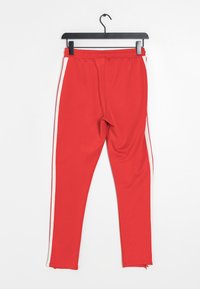 Rode sportieve broek met witte zijkanten, gemaakt van een gladde, rekbare stof. Voorzien van een elastische tailleband en een getailleerd ontwerp.