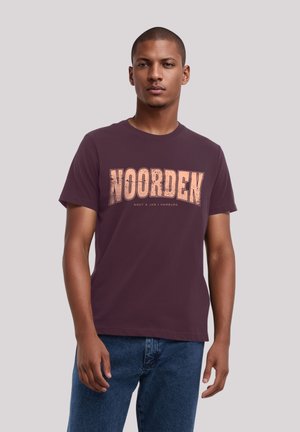 Maroon cotton t-shirt with bold "NOORDEN" graphic in light orange. Short sleeves, crew neck, relaxed fit. Model wears denim jeans.