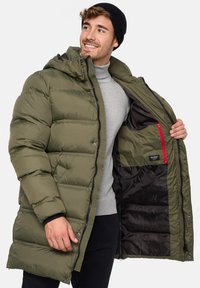Olivengrøn pufferjakke med hætte, der har lynlås, sort indvendig foring og en rød lynlåslomme. Quittet design med glinsende struktur.