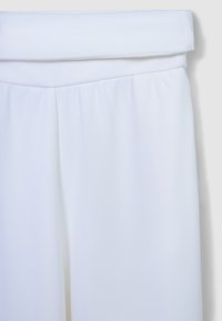 Haut sans manches blanc avec un col plié, texture lisse et tissu froncé à la taille. Design simple sans motifs visibles.