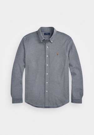 Button-up shirt in dark blue fabric with a textured pattern. Features a spread collar, long sleeves, and a small embroidered logo on the chest.