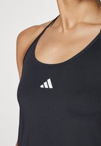 Must on must lõikega must sportlik särk, millel on peened õled. Rinna kohal on valge adidas'i logo. Sile tekstuur.