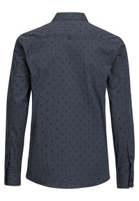 Košile s dlouhým rukávem v tmavě šedé látce s jemným opakujícím se vzorem černých blesků; má klasický límec a manžety na knoflíky.