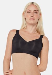 Sostén inalámbrico negro con tirantes anchos, escote en V, textura suave y copas con un diseño sutil para brindar confort y soporte.