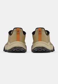 Ανοιχτό καφέ ορειβατικά παπούτσια με μαύρη λαστιχένια σόλα, πορτοκαλί λουράκι στο πίσω μέρος και υφή στο επάνω μέρος με γεωμετρικά σχέδια.