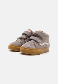 Zapatillas altas de ante gris con dos tiras de velcro, acentos laterales blancos y una suela de goma. Superficie superior texturizada con perforaciones.