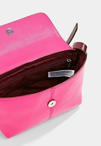 Różowa skórzana torebka na ramię z górną klapą, wewnętrzną kieszonką na zamek i brązowym wykończeniem. Posiada srebrne zapięcie na zatrzask oraz gładką fakturę.