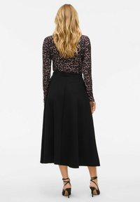 Černá áčková sukně s hladkým povrchem, doplněná dlouhým rukávem a vrškem s fialovým leopardím potiskem. Podpatky dotvářejí outfit.