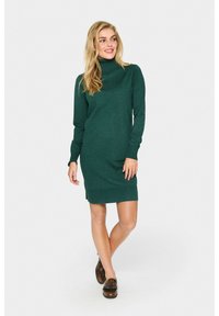 Vestido de punto verde oscuro con mangas largas y cuello alto. Presenta una textura acanalada y una silueta ajustada, que termina por encima de la rodilla.