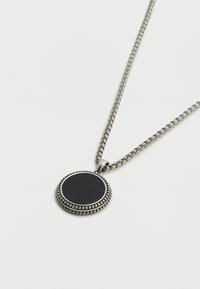 Collier chaîne argentée avec un pendentif rond noir bordé de perles, texture lisse et finition polie.