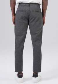 Gray textured trousers with a slim fit, featuring a flat front, two back pockets, and worn with white sneakers.