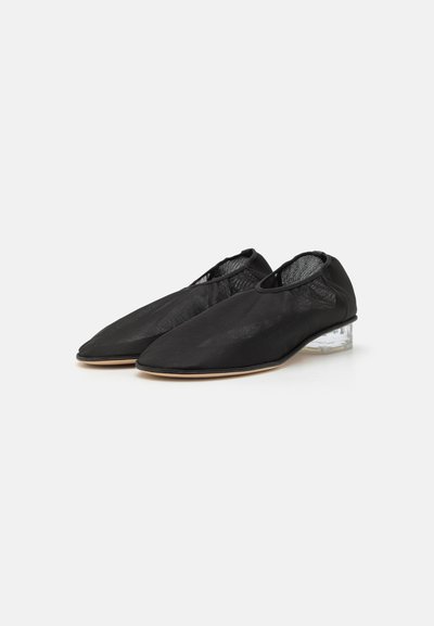 Scarpe nere in rete con design a punta, tacco a blocco trasparente e tomaia con texture liscia. Presentano una costruzione minimalista e nessuna ferramenta visibile.