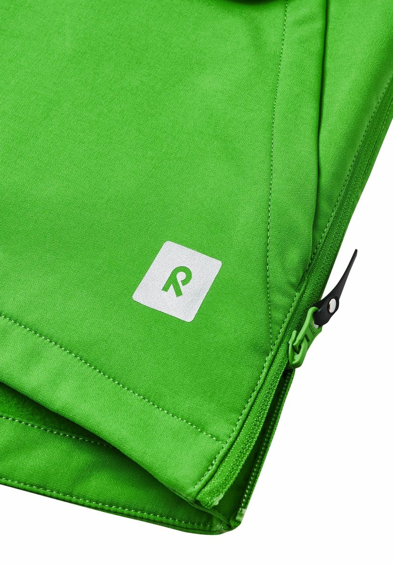 Zielona tkaninowa torba o gładkiej fakturze, z białą metką logo i czarnym zamkiem błyskawicznym po boku. Widać zagięte krawędzie.