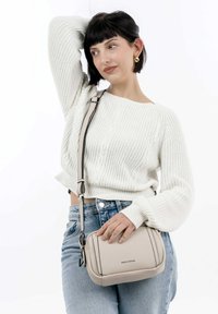 Borsa a tracolla beige realizzata in pelle texturizzata, con una forma strutturata, tracolla regolabile e un accento con il marchio sulla parte anteriore.