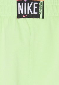 Nike drabužis su gyvybinga šviesiai žalia medžiaga, su juodu etiketė, ant kurios yra balti ir rožiniai užrašai, ir lygiu paviršiumi.