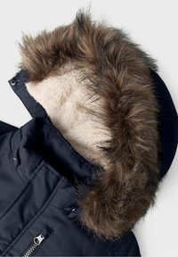 Granatowa zimowa kurtka z kapturem, podszewką z beżowego polaru i wykończeniem z grubego, brązowego sztucznego futra, z widocznymi detalami zamka błyskawicznego i guzików zatrzaskowych.