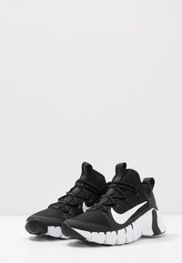 Et par sorte mesh sportsko med hvide Nike swoosh-logoer og hvide segmenterede såler på hvid overflade og baggrund.