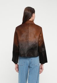 Braune und schwarze Ombré-Lederjacke mit einem cropped Design, weiten Ärmeln und einem Kragen. Die Textur ist weich und hat einen dezenten Glanz.