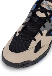 Smėlio spalvos ir juodos spalvos sportbačiai iš tinklelio ir sintetinių medžiagų, su mėlynomis detalėmis, išraiškinga batraiščių sistema ir tekstūruotu padu.
