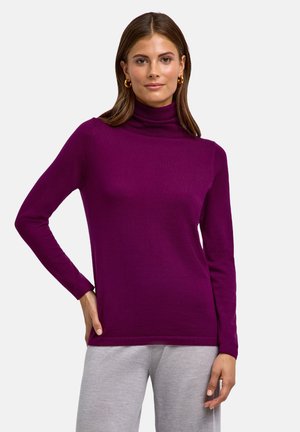 Maglione a collo alto aderente di un vivace colore viola. Tessuto a maglia morbido con maniche lunghe e una texture liscia. L'orlo si trova a livello dei fianchi.
