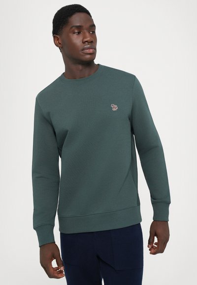 Sudadera de color verde oscuro hecha de una mezcla de algodón, con cuello redondo, mangas largas y un pequeño logo en el pecho. Textura suave.