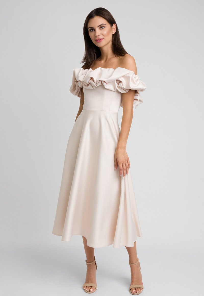 Sukienka odsłaniająca ramiona w jasnym beżu z falbaniastymi rękawami, dopasowanym korpusem i luźną spódnicą w kształcie litery A, wykonana z gładkiego materiału.